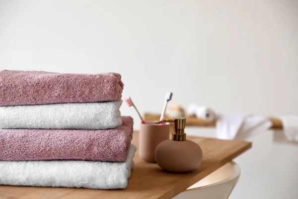 Pila de toallas suaves limpias, dispensador de jabón y cepillos de dientes en el baño —  Fotos de Stock