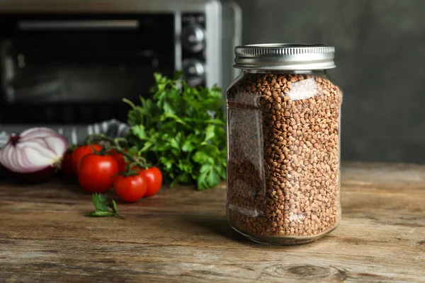 Buckwheat grains in jar on wooden table. Space for text — Stock Photo, Image