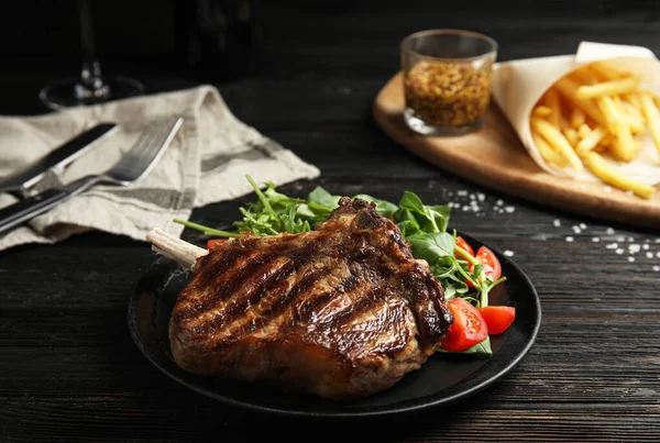 Lekkere gegrilde biefstuk met salade op zwarte houten tafel — Stockfoto