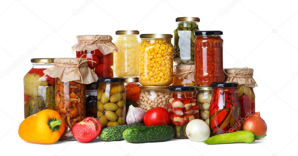 Fresh vegetables and jars of pickled products on white background