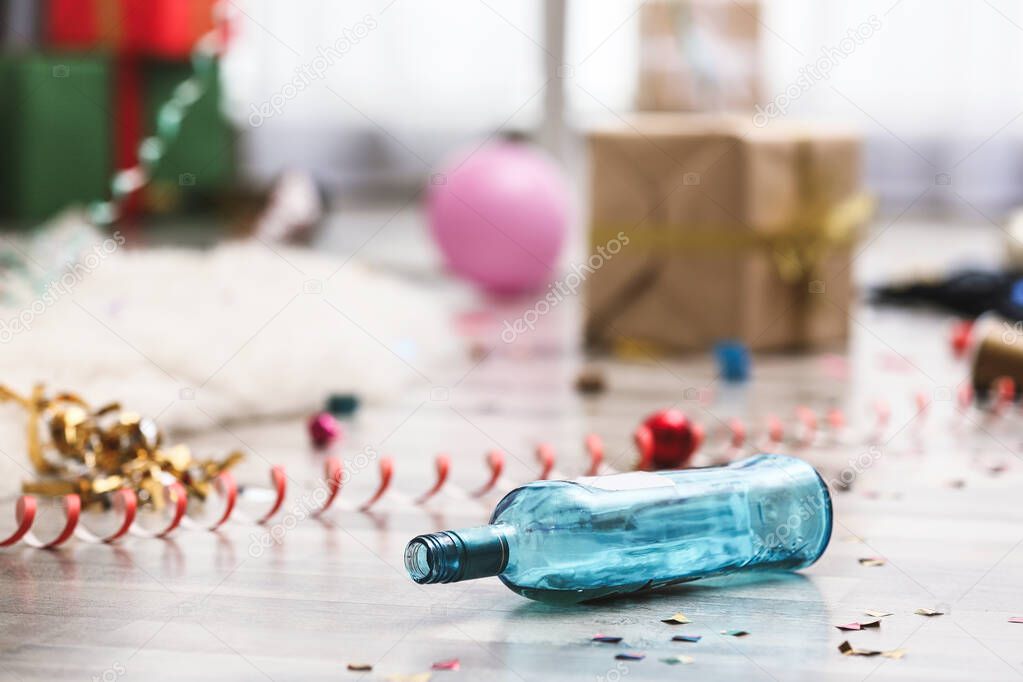 Empty bottle and confetti on messy floor. Chaos after party