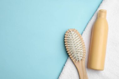 Açık mavi arka planda fırça ve şampuan şişesiyle düz kompozisyon, metin için boşluk. Saç bakım kozmetik ürünleri