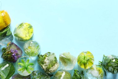 Çiçekli buz küpleri ve açık mavi arka planda yapraklar düz yerde. Metin için boşluk