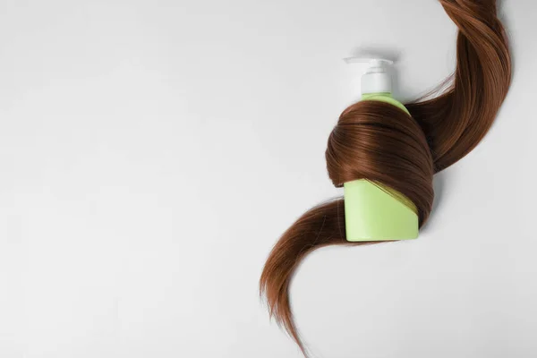 Butelka szamponu owinięte w blokadę włosów na białym tle, widok z góry. Naturalne produkty kosmetyczne — Zdjęcie stockowe