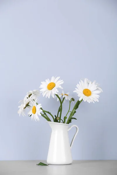Piękne delikatne kwiaty rumianku w dzbanku na stole na jasnym tle — Zdjęcie stockowe