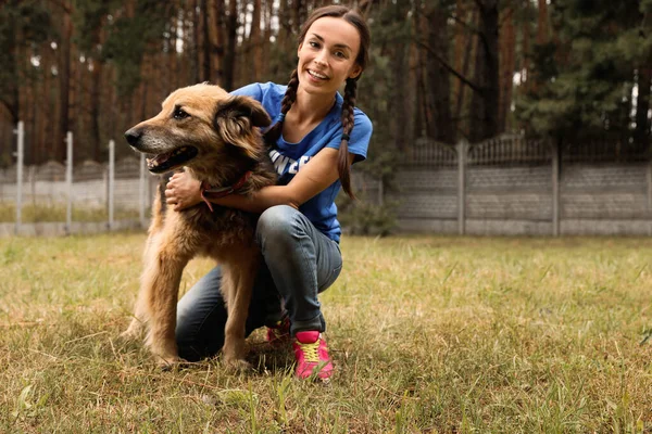 Mujer voluntaria con perro sin hogar en refugio de animales al aire libre — Foto de Stock