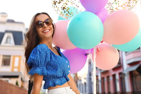 Schöne junge Frau mit bunten Luftballons auf der Straße der Stadt — Stockfoto