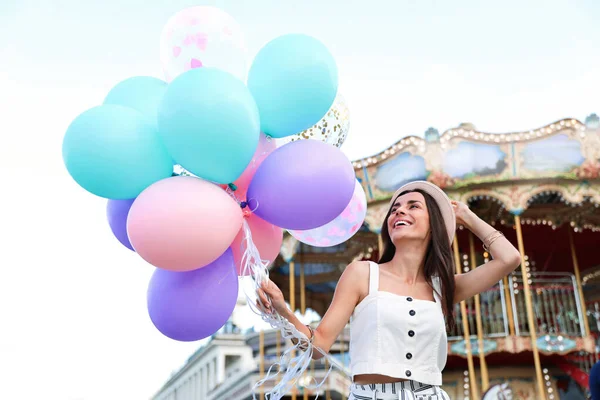 Atrakcyjna młoda kobieta z balonami w pobliżu karuzeli — Zdjęcie stockowe