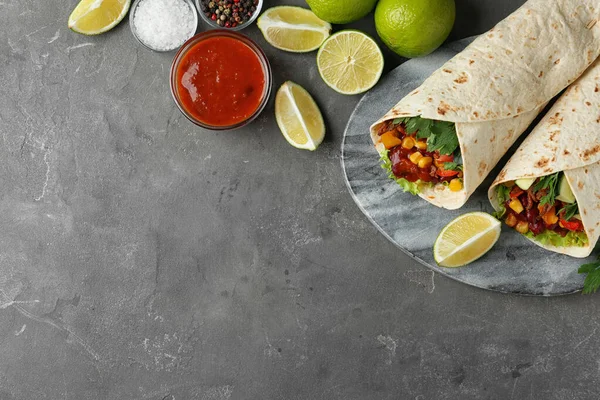 Placa com deliciosos envoltórios de tortilla de carne em mesa cinza, flat lay. Espaço para texto — Fotografia de Stock