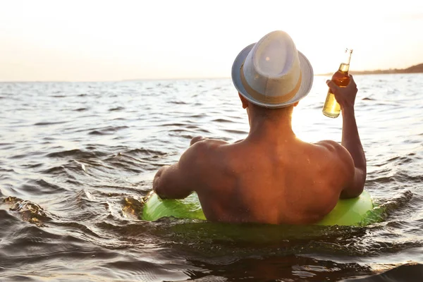 Anak muda dengan minuman di cincin tiup di laut — Stok Foto