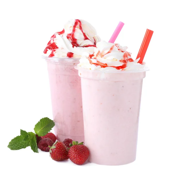 Savoureux milk shakes frais dans des tasses en plastique avec des ingrédients sur fond blanc — Photo