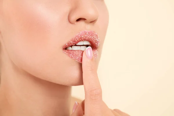Young woman with sugar scrub on lips against beige background, closeup — ストック写真