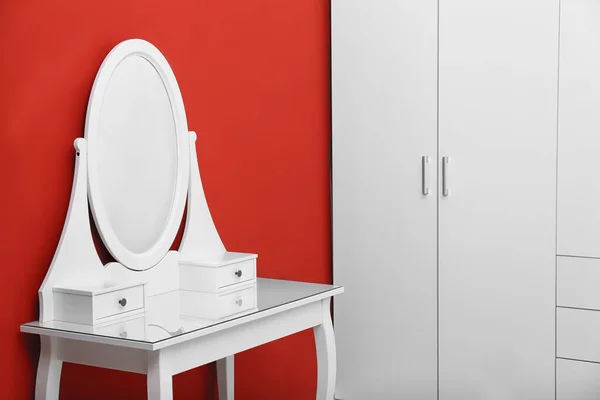 Елегантний білий стіл для макіяжу біля червоної стіни — стокове фото