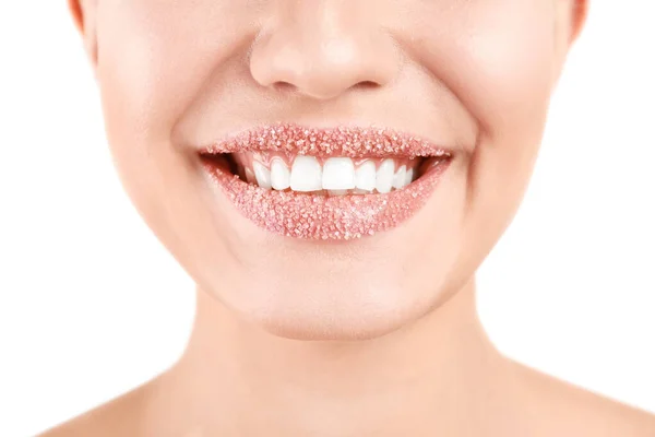 Mujer joven con exfoliante de azúcar en los labios sobre fondo blanco, primer plano — Foto de Stock