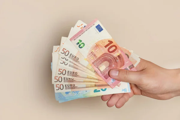 Hombre con billetes en euros sobre fondo marrón, primer plano — Foto de Stock