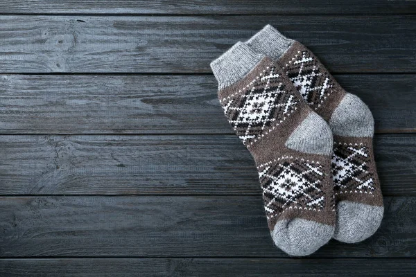 Warm knitted socks on black wooden background, flat lay. Space for text — Stock Photo, Image