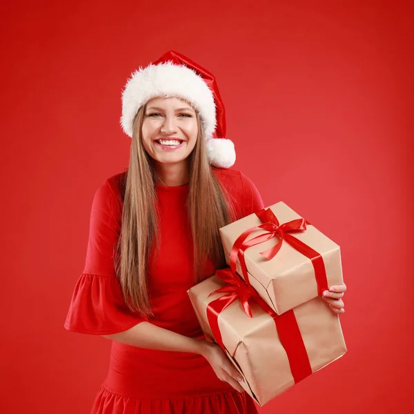 戴着圣诞礼帽、背景为红色的快乐年轻女子 — 图库照片