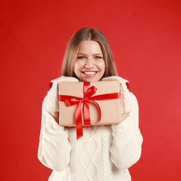 Счастливая молодая женщина с подарком на Рождество на красном фоне — стоковое фото