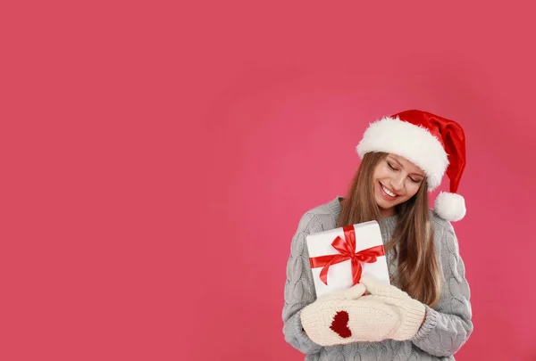 Joyeux jeune femme en chapeau de Père Noël avec cadeau de Noël sur fond rose. Espace pour le texte — Photo