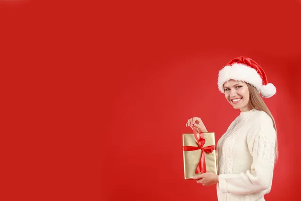 快乐的年轻女人戴着圣诞礼帽,背景是红色的. 案文的篇幅 — 图库照片