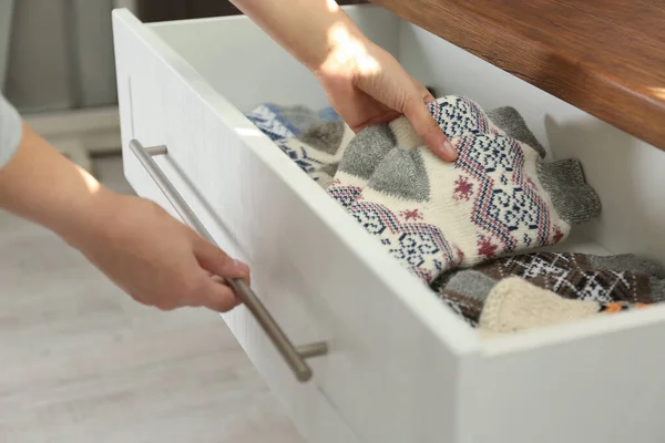 Женщина вынимает теплые вязаные носки из ящика в помещении, крупным планом — стоковое фото