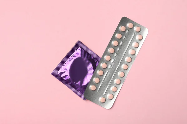 Préservatif et pilules contraceptives sur fond rose, vue de dessus. Sexe sans risque — Photo