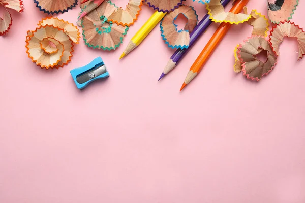 Lápis de cor, apontador e raspas no fundo rosa, vista superior. Espaço para texto — Fotografia de Stock