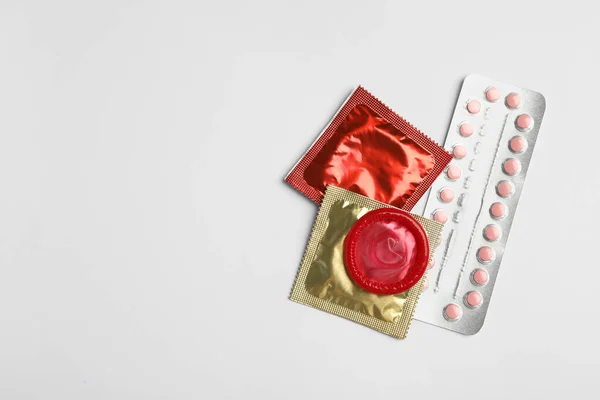 Los condones y las píldoras anticonceptivas sobre fondo gris claro, planas yacían con espacio para el texto. Concepto de sexo seguro — Foto de Stock