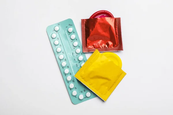 Píldoras anticonceptivas y condones sobre fondo blanco, vista superior. Concepto de sexo seguro — Foto de Stock
