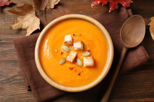 Bowl with tasty pumpkin cream soup on wooden table, flat lay — Stok fotoğraf