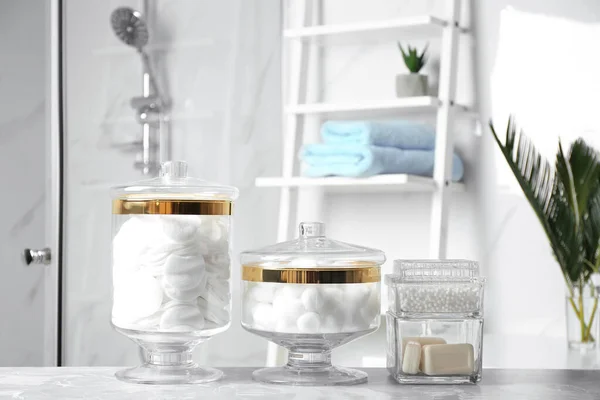 Cotton balls, swabs, pads and soap bars on light grey marble table in bathroom — 스톡 사진