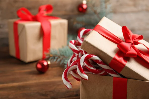 Bastones de caramelo en caja de regalo sobre mesa de madera, espacio para texto. Tradicional regalo de Navidad — Foto de Stock