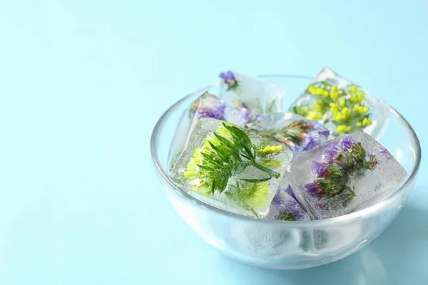 Cuenco de cubitos de hielo con flores sobre fondo azul. Espacio para texto — Foto de Stock