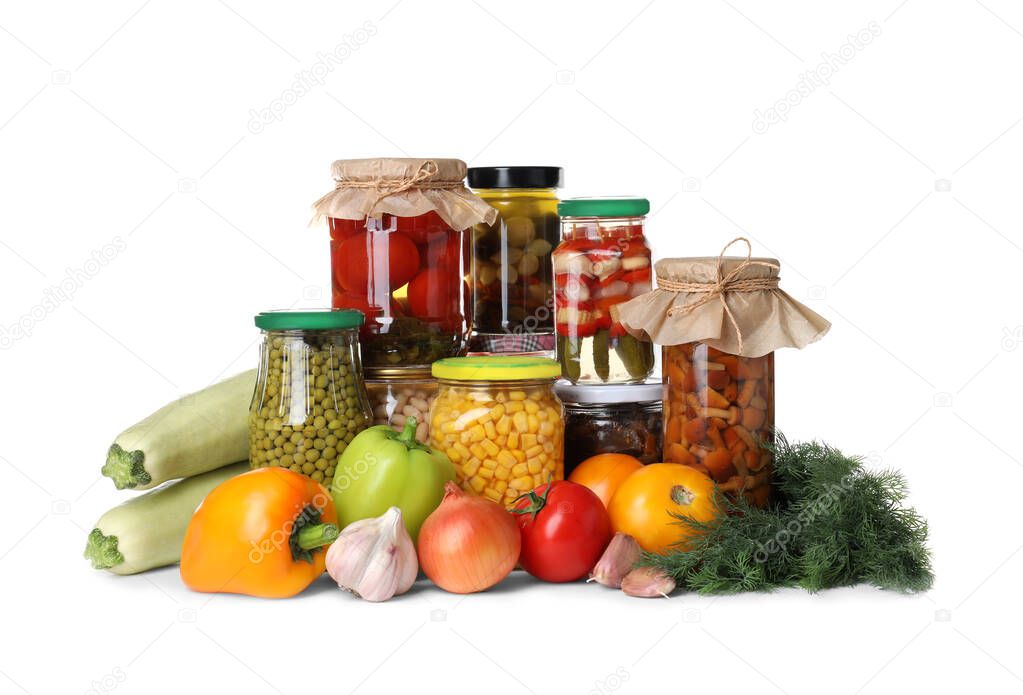 Fresh vegetables and jars of pickled products on white background