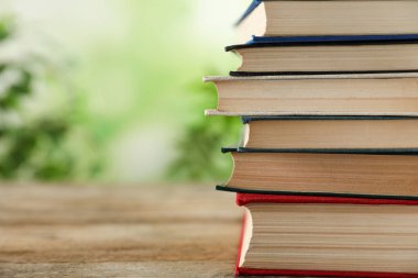 Ahşap masanın üzerinde arka planda bulanık duran bir yığın kitap. Metin için boşluk