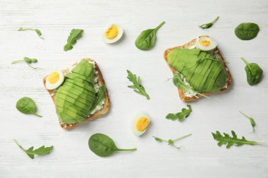 Flat lay composition with avocado toasts on white wooden table