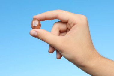 Mavi arka plana karşı agate değerli taş tutan kadın, yakın plan.