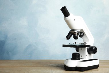 Modern mikroskop ahşap masada mavi arka plana karşı, yazı için alan. Tıbbi ekipman