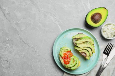 Açık gri masada avokado sandviçli düz kompozisyon. Metin için boşluk