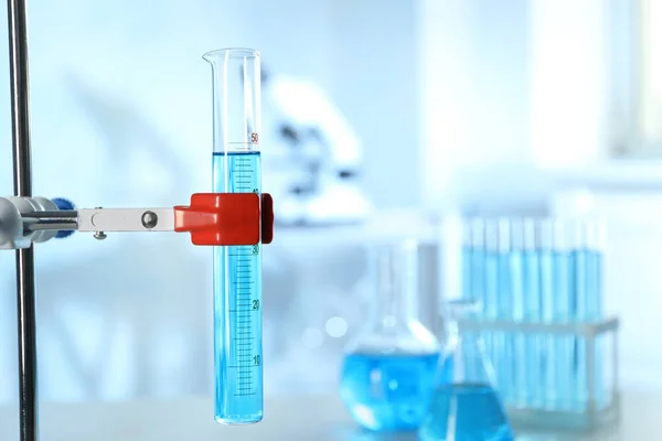 Cilindro graduado con líquido azul claro en laboratorio. Espacio para texto — Foto de Stock