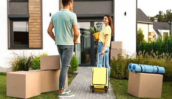 Couple walking to their new house with moving boxes and household stuff