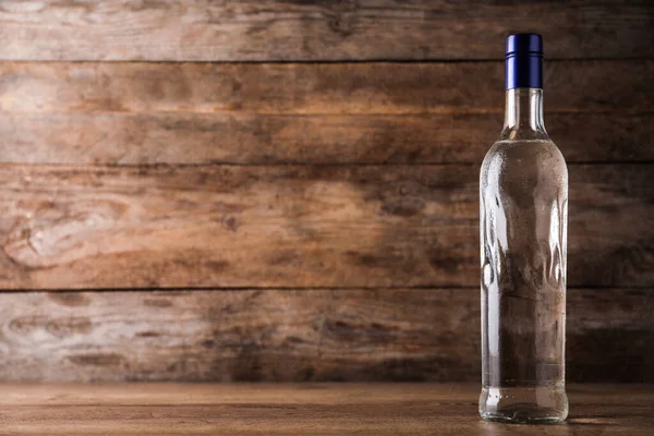 Bottle of vodka on table against wooden background. Space for text — Stockfoto
