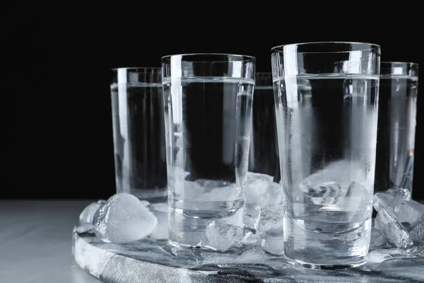 Vodka em copos de tiro e gelo na mesa cinza, close-up — Fotografia de Stock