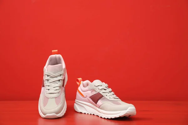 Elegantes zapatillas de mujer en mesa de madera cerca de la pared roja —  Fotos de Stock