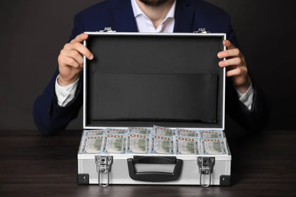 Geschäftsmann mit Fall von Dollarscheinen am Holztisch, Nahaufnahme — Stockfoto