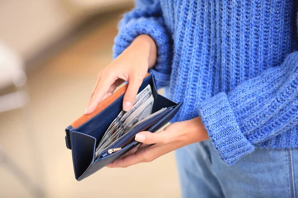 Jeune femme tenant portefeuille avec des billets de dollar sur fond flou, gros plan — Photo
