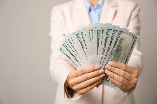 Mladá žena drží dolarové bankovky na světle šedém pozadí, detailní záběr — Stock fotografie