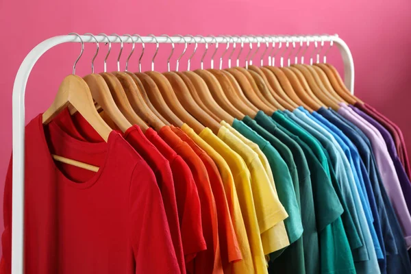 Bastidor con ropa brillante sobre fondo rosa. Colores del arco iris —  Fotos de Stock
