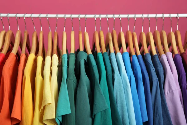 Rack fényes ruhák rózsaszín háttér. Szivárvány színek — Stock Fotó