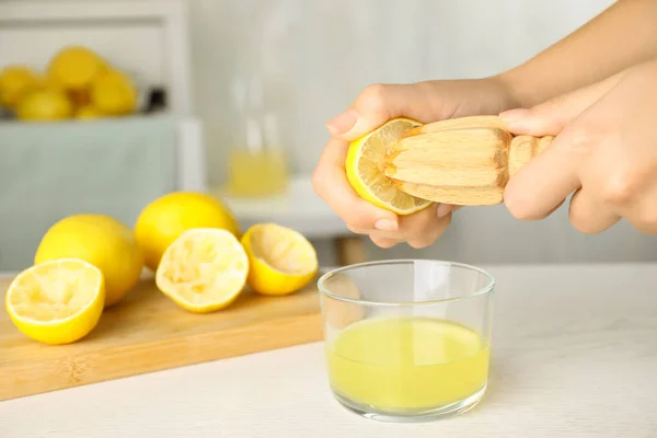 Femme serrant du jus de citron avec alésoir à table blanche en bois, gros plan. Espace pour le texte — Photo